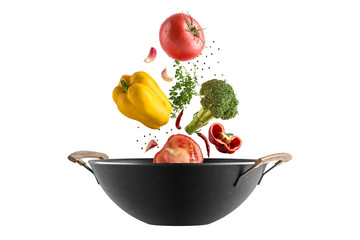Fresh multicolored vegetables fly over a wok frying pan. White isolated background.