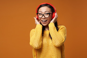 Young woman in glasses is listening to music in red headphones