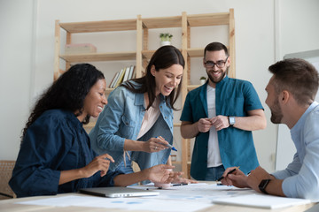 Overjoyed diverse businesspeople have fun engaged in creative thinking at team briefing in office,...