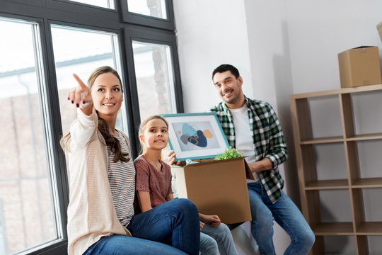 mortgage, family and real estate concept - happy mother, father and little daughter with stuff in boxes moving to new home