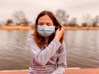 a teenage girl taking off a medical mask