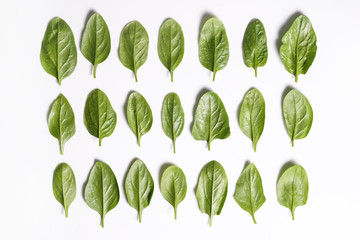 Clean eating concept. Leaves ripe juicy freshly picked organic baby spinach greens laid in pattern, isolated on white background. Healthy diet for spring summer detox. Vegan raw food. Close up.