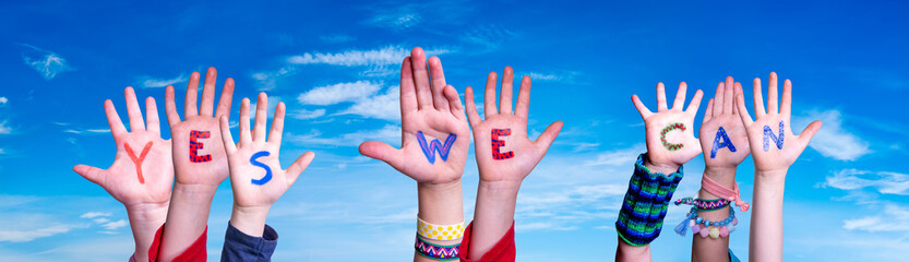 Children Hands Building Colorful Word Yes We Can. Blue Sky As Background