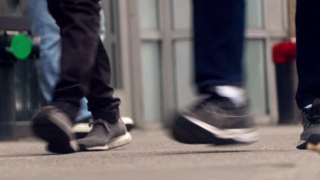 People walk on the street, close up to feet, shoes, boots, sneakers. Day time, busy street. Spring time.