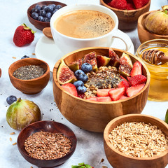 Healthy breakfast and breakfast ingredients, oatmeal with fruits and berries, figs, blueberries, strawberries, flax and chia seeds, honey.