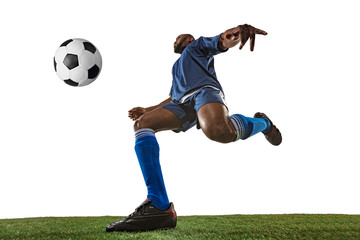 Football or soccer player on white background with grass. Young male sportive model training, practicing. Attacking, catching. Concept of sport, competition, winning, motion, overcoming. Wide angle.