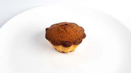 Sweet homemade cupcake with raisins on a white plate.