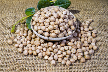 Chickpeas: composition of chickpeas with wooden container on a raw yuta canvas background.