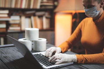 Woman with protective antiviral mask surfing the internet for searching and buying toilet paper.