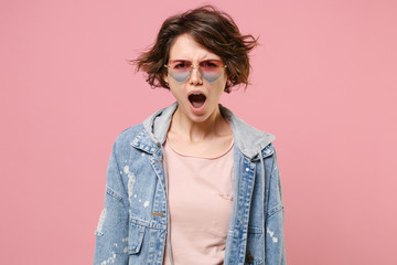 Shocked irritated young brunette woman girl in casual denim jacket eyeglasses posing isolated on pastel pink wall background studio portrait. People lifestyle concept. Mock up copy space. Swearing.