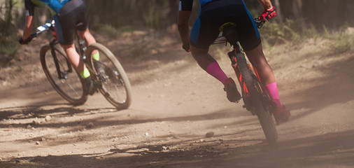 Athletes mountain biking on forest trail, mountain bike race	
