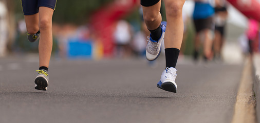 Running children, young athletes run in a kids run race,running on city road detail on legs	