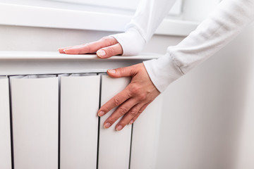 Heavy duty radiator - central heating. Woman is getting her hands warm on Home central heating system