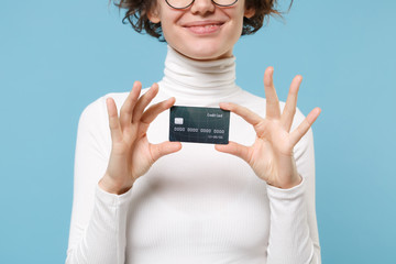 Cropped image of young brunette woman girl in casual white clothes eyeglasses posing isolated on pastel blue background in studio. People lifestyle concept. Mock up copy space. Hold credit bank card.
