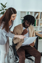 Employee pointing with pen at papers in african american male hands in office