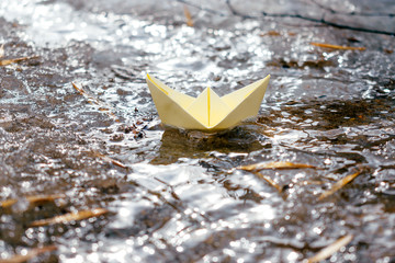  Yellow paper boat sails along the stream. Spring concept.Concept of travel during coronavirus...