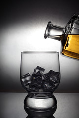 bartender pours rum from a decanter into an ice glass, vignetting