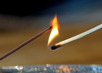 Close up of a burning match lighting a incense stick