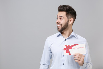 Excited young unshaven business man in light shirt posing isolated on grey background in studio....