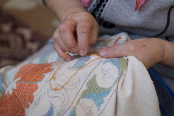 Woman embroiders suzani close up. A type of embroidered and decorative tribal textile made in Uzbekistan