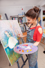 Vertical shot of a female artist working on a painting on canvas at art studio