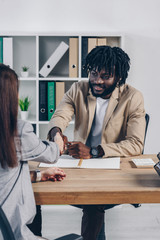 Cropped view of african american recruiter shaking hands with employee at job interview in office