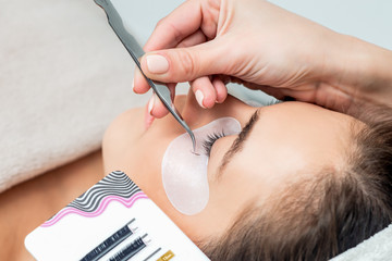 Young woman receiving eyelash extension procedure in beauty salon.