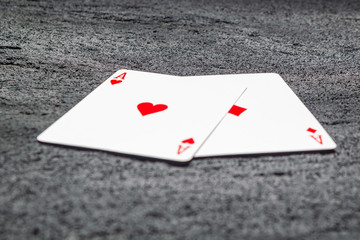 two red aces heart and diamond on black concrete dark background .copy space