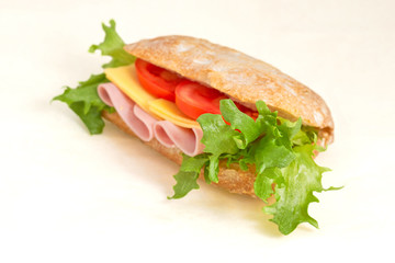 Sandwich with lettuce, ham and tomatoes and cheese. Closeup on a light background