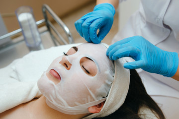 Face peeling mask, spa beauty treatment, skincare. Woman getting facial care by beautician at spa salon.