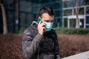 Men using phone in face mask on the street	