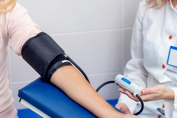 Doctor measures the pressure of young woman close up.