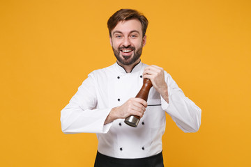 Funny young bearded male chef cook or baker man in white uniform shirt posing isolated on yellow...