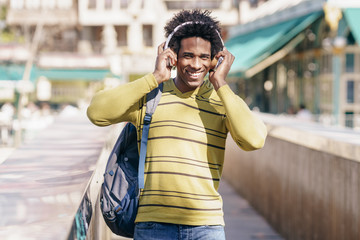 Black man listening to music with wireless headphones sightseeing in Granada