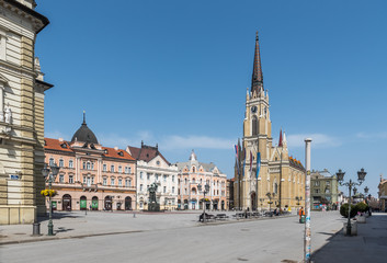 Fototapeta premium Novi Sad, Serbia city center with cathedral and old buildings with small group of people almost empty during the coronavirus or covid-19 isolation.