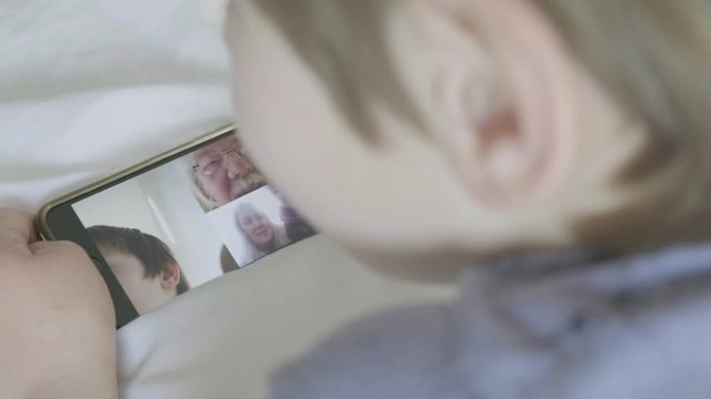 Rear view of a caucasian boy making a video call to his family themes of technology communication video call