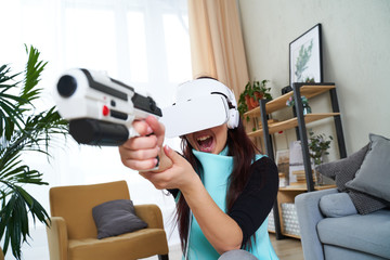 Woman with virtual reality headset and blaster is playing game.