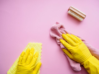 Hände in gelben Gummihandschuhen und  mit rosa Putzlappen auf einem pinken Hintergrund, Flat lay,...