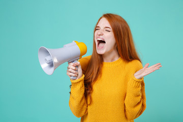 Crazy young redhead woman girl in yellow sweater posing isolated on blue turquoise background. People lifestyle concept. Mock up copy space. Scream in megaphone, keeping eyes closed, spreading hands.