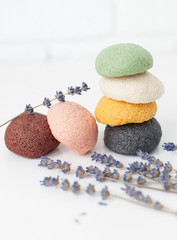 natural sponge konjac for face and body care, cleansing sponge in different colors on a white background with lavender flowers, with place for text