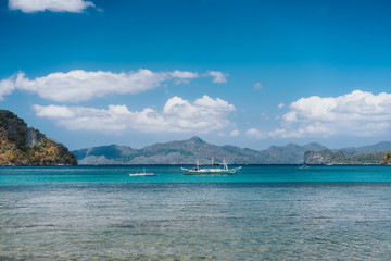 Fototapeta na wymiar Filippino boats in open ocean in El Nido bay. Islands shapes in background. Palawan island, Philippines