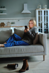 Obraz premium Woman use of smartphone in the evening at home while laying on sofa