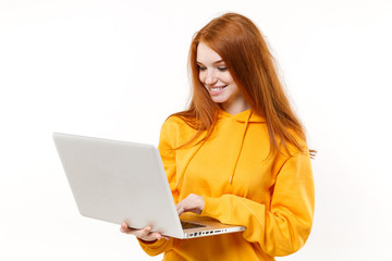 Naklejka premium Smiling young redhead woman girl in yellow hoodie posing isolated on white background studio portrait. People sincere emotions lifestyle concept. Mock up copy space. Working on laptop pc computer.