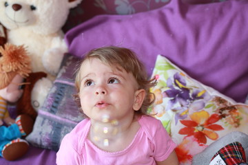 Cute little Caucasian girl one year old plays in her room with soap bubbles, laughs merrily, close-up. Childhood, leisure, games.