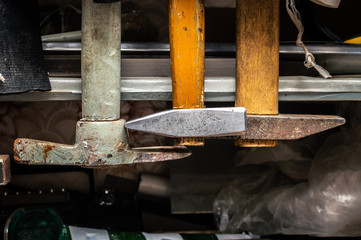 Three old hammers hang on the wall of an old-school workshop