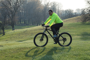 Cyclist in pants and green jacket on a modern carbon hardtail bike with an air suspension fork. The guy on the top of the hill rides a bike.