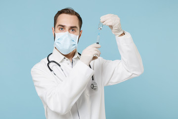 Doctor man in gown face mask gloves isolated on blue background. Epidemic pandemic coronavirus...