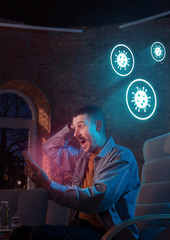 Shocked, upset and sad caucasian man using gadgets to get information of coronavirus pandemic spread. Staying at home to be safe. Analyzing situation with world's count of cases, healthcare, medicine.