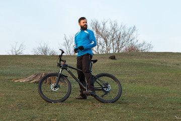 Fototapeta premium Cyclist in pants and fleece jacket on a modern carbon hardtail bike with an air suspension fork. The guy on the top of the hill rides a bike.