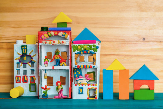 A toy house made of a box from juice and a plasticine family living in it. Creative paper bag ideas. Recycle crafts.